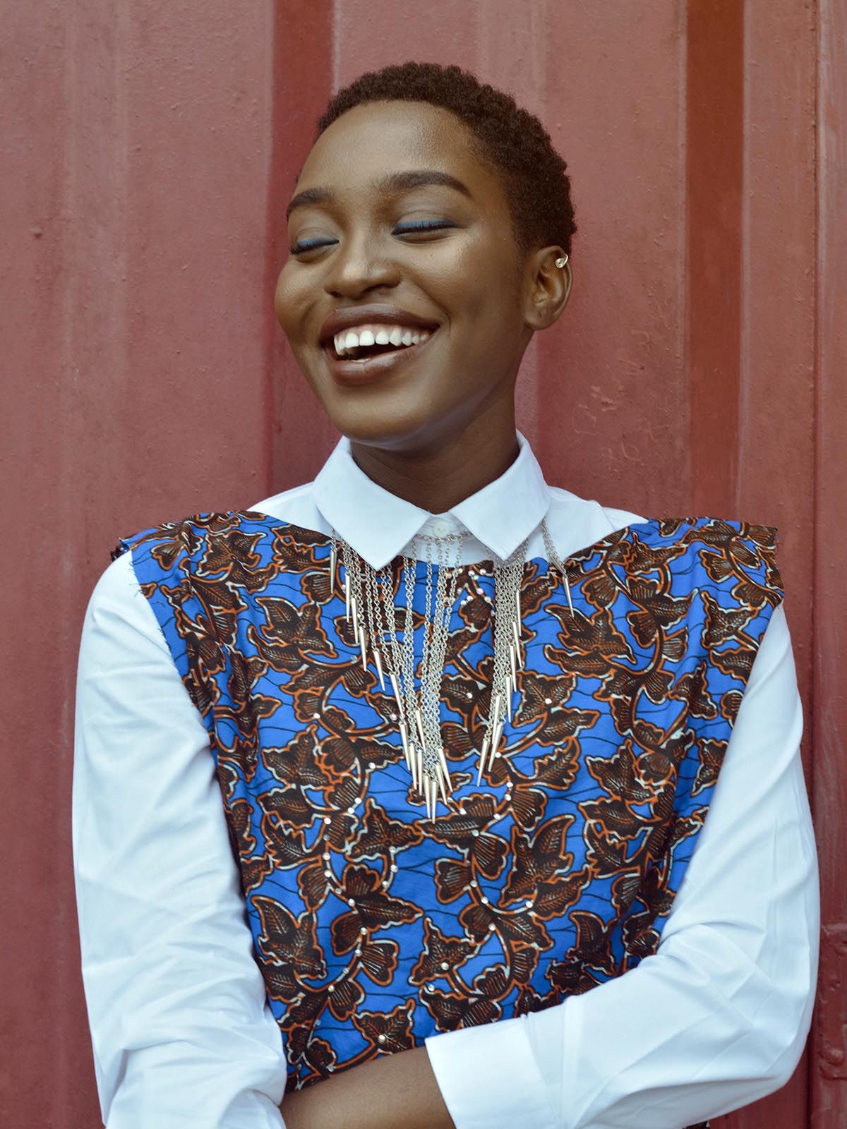 En leendes kvinna med stängda ögon mot en röd vägg